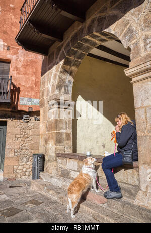 Eine blonde Frau eine Pause ein Sandwich zu essen und haben einige Kaffee mit ihrem blonden Border Collie mix Hund unter einem Torbogen auf dem alten kleinen Stein Stockfoto