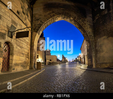 Prag in der Morgendämmerung, Eingang zur Karlsbrücke durch die beleuchteten Bogen von Lesser Town Bridge Tower in den frühen Morgenstunden. Panoramic Image, sq Stockfoto