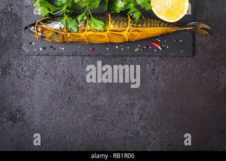 Geräucherte Makrele Fisch auf schwarzen Stein Hintergrund. Stockfoto