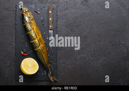 Geräucherte Makrele, Messer und Zitrone auf schwarzen Stein Schneidbrett, kopieren. Stockfoto