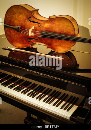 Cello und Bogen auf Grand Piano mit Sahne Hintergrund Stockfoto