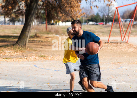 Vater und Sohn spielen Basketball im Park Stockfoto