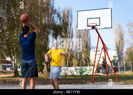 Senior Vater und Sohn spielen Basketball im Park Stockfoto