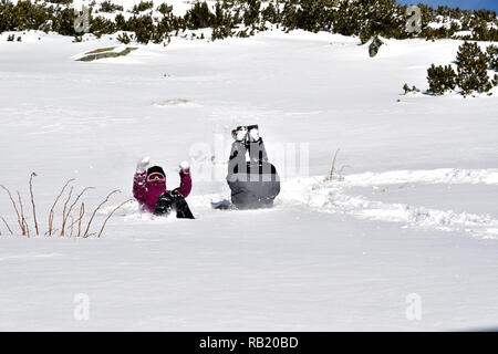 Familie spielen im Wäschetrockner auf dem Schnee in den Bergen Stockfoto