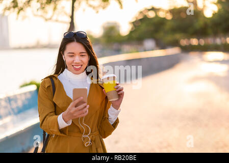 Fröhliches Mädchen mit Telefon und eine Tasse Kaffee im Freien Stockfoto