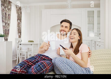 Ein Mädchen und ein Kerl Fernsehen sitzen auf dem Sofa im Zimmer. Stockfoto