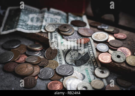 -Scheine und Münzen auf dem Boden mit Beton und Holz- Box als Kulisse verstreut. Vintage Gefühl. Münzen, Geld, Dollar, mit antiken conce Stockfoto