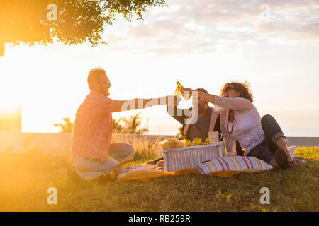 Gruppe von Freunden Menschen in Outdoor Freizeitaktivitäten Aktivität klirren mit einigen Bierflaschen alle zusammen Spaß und Freundschaft während eines goldenen b Stockfoto