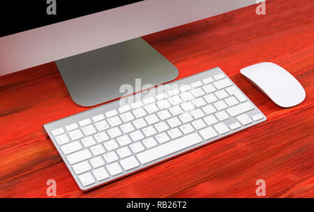 Business Arbeitsplatz mit Computer, drahtlose Tastatur und Maus auf alten roten hölzernen Tisch Hintergrund. Schreibtisch mit Kopie Raum Stockfoto