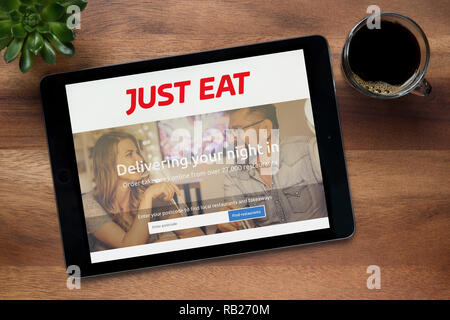 Die Website von nur Essen ist auf einem iPad Tablet gesehen, auf einer hölzernen Tisch zusammen mit einem Espresso und einem Haus Anlage (nur redaktionelle Nutzung). Stockfoto