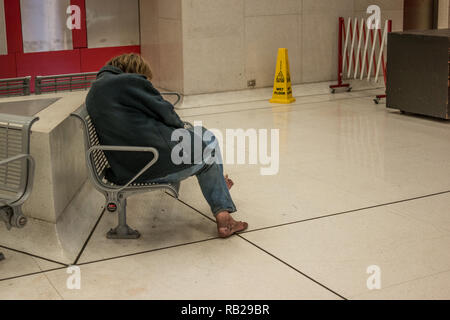 Obdachlosen schläft auf der Bank in der Nähe der U-Bahn Station Stockfoto