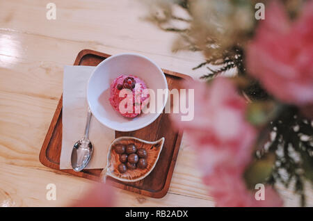 Schokolade Eis in ein Glas Schale mit Blumen auf Holz Tisch. Stockfoto