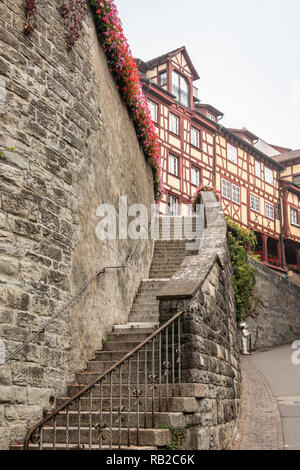 Hohe Steinmauer mit eine lange Treppe zu einigen alten mittelalterlichen Häusern Stockfoto