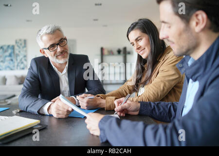 Attraktive Paar unterzeichnen Vertrag mit real-estate agent in der zeitgenössischen Haus Stockfoto