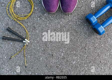 Motiviert zum Training. Zwei blaue dumpbells und Seil springen liegen in der Nähe von Purple Sport Schuhe. Fitness als Hobby Stockfoto