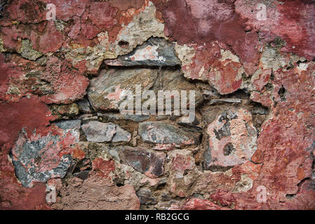 Antike Mauer aus Stein mit einer bunten Textur in rot lackierte Töne Stockfoto