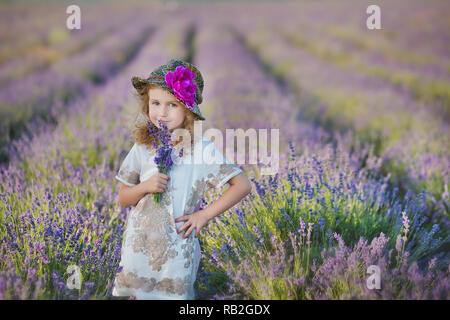 Junge schöne Mädchen zu Fuß auf der Lavendel Feld an einem Tag am Wochenende im wunderschönen Kleider und Hüte Stockfoto