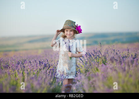 Junge schöne Mädchen zu Fuß auf der Lavendel Feld an einem Tag am Wochenende im wunderschönen Kleider und Hüte Stockfoto