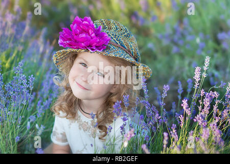 Junge schöne Mädchen zu Fuß auf der Lavendel Feld an einem Tag am Wochenende im wunderschönen Kleider und Hüte Stockfoto