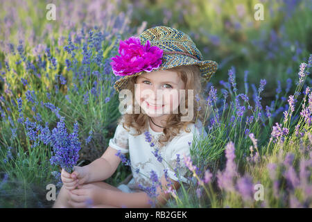 Junge schöne Mädchen zu Fuß auf der Lavendel Feld an einem Tag am Wochenende im wunderschönen Kleider und Hüte Stockfoto