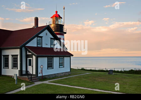 Sonnenuntergang von West Quoddy Head Lighthouse in Maine mit dem markanten roten und weißen Streifen. Sie ist die am nord-östlichen Leuchtfeuer in Amerika. Stockfoto