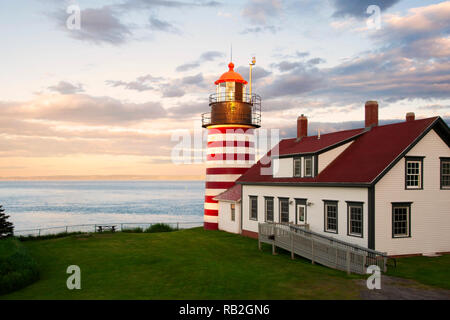 Sonnenuntergang von West Quoddy Head Lighthouse, mit seinen roten und weißen Streifen, bezeichnet als die "Candy Cane" Leuchtturm, im Osten Maine, in Neu-england. Stockfoto