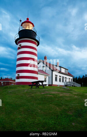 Sturmwolken wie Licht erstrahlt der West Quoddy Head Lighthouse, eine rot-weiss gestreifte Leuchtturm in Northern Maine, in Neu-england. Turm s Stockfoto