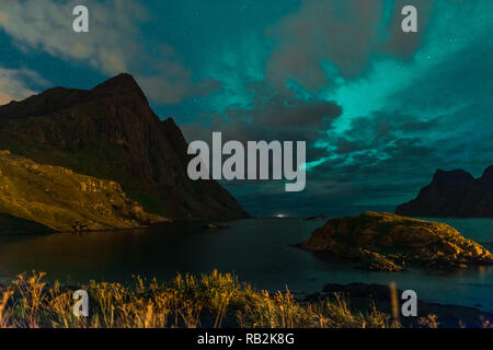 Aurora über Sandstrand haukland, Kvalvika und Skagsanden mit Steinen in Norwegen, Lofoten. Nordlicht in Lofoten Inseln, Norwegen. Sternenhimmel mit Polarlichter. Nacht Landschaft mit grünen Aurora borealis, Felsen, Licht. Stockfoto