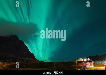 Aurora über Sandstrand haukland, Kvalvika und Skagsanden mit Steinen in Norwegen, Lofoten. Nordlicht in Lofoten Inseln, Norwegen. Sternenhimmel mit Polarlichter. Nacht Landschaft mit grünen Aurora borealis, Felsen, Licht. Stockfoto