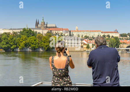 Prag, tschechische Republik - Juli 2018: Mann und Frau Bilder von einem Fluss Bootsfahrt auf der Moldau in Prag. Im Hintergrund ist St Vita Stockfoto