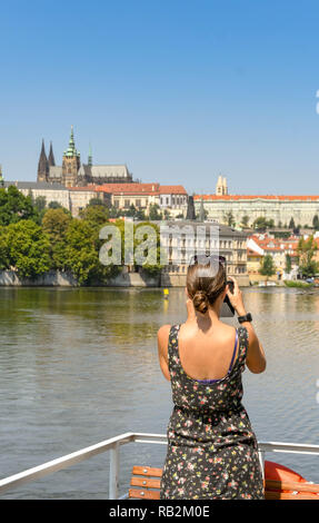 Prag, tschechische Republik - Juli 2018: Person, die Bilder von einer Schifffahrt auf der Moldau in Prag. Im Hintergrund ist St. Vitas Kathedrale Stockfoto