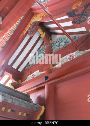 Nahaufnahme der reich verzierten, Rot hölzerne Dachkonstruktion auf das Gebäude am Tsurugaoka Hachimangu Shinto Schrein, Kamakura, Japan Stockfoto