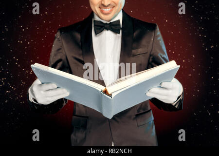 Berufliche Tätigkeit. Magier in Anzug und Handschuhe an der Wand lesen Magic freudige schließen isoliert aufstehen Stockfoto