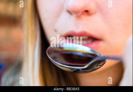 Junge Frau nimmt Husten Sirup Stockfoto