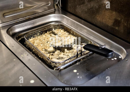 Gebratenes Fleisch oder Kartoffel in einer Friteuse. Zubereitung von Speisen im Restaurant Stockfoto