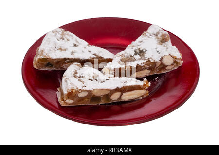 Panforte Slices auf rote Platte, isoliert auf Weiss. Italienische Weihnachten süße Nachspeise, Kuchen machen mit getrockneten Früchten und Nüssen. Stockfoto