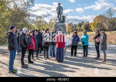 Touristen an der Minuteman Statue an der alten Nordbrücke in Concord, MA versammelt Hören zu einem Park Reiseführer Stockfoto