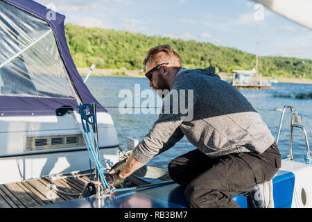 Junger Mann heben das Segel Katamaran während der Kreuzfahrt Stockfoto
