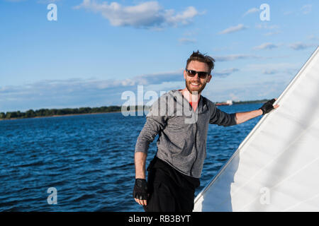 Junger Mann heben das Segel Katamaran während der Kreuzfahrt Stockfoto