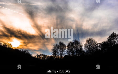 Sonnenuntergang mit dramatischen Himmel mit Wolken und Silhouetten von Bäumen Stockfoto