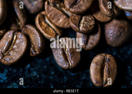 Kaffeebohnen auf schwarzem Marmorhintergrund, Makrofotografie, Details Stockfoto