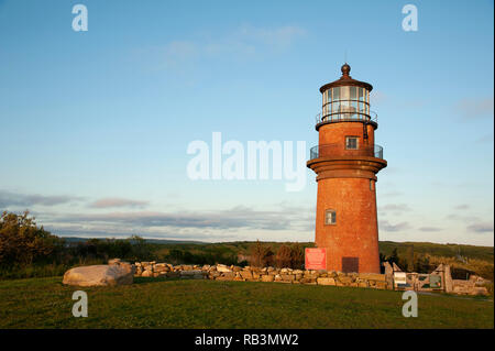 Aquinnah Leuchtturm, auch als Gay, sitzt auf einem Hügel, durch eine Mauer aus Stein und Holz- Tor umgeben, wie die Sonne auf Martha's Vin Sets Stockfoto