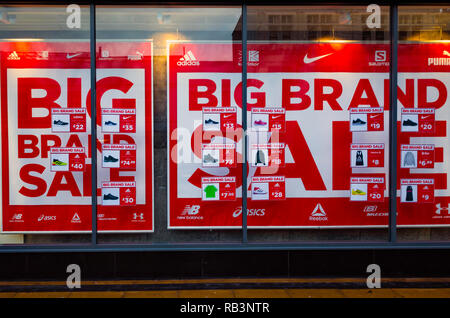 Schaufenster für eine nationale Kette mit Plakaten mit Verkauf von grossen Marken zu reduzierten Preisen am 18. Dezember zeigen, Schwierigkeiten bei der Th gefüllt Stockfoto