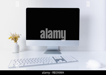 Sauber und minimalistisch Büro Arbeitsplatz mit Computer. Vorderansicht des PC, Handy, Papiere und numerische Tastatur auf sauberen weißen Tisch Stockfoto