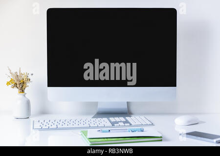 Sauber und minimalistisch Büro Arbeitsplatz mit Computer. Vorderansicht des PC, Handy, Papiere und numerische Tastatur auf sauberen weißen Tisch Stockfoto