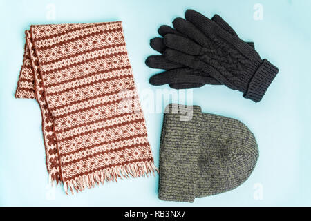 Blick von oben auf die Winter Kleidung Accessoires für den Einsatz im Freien. Stricken - Hut Mütze, Winterhandschuhe und Wolle Schal ordentlich auf hellblauem Hintergrund organisiert Stockfoto