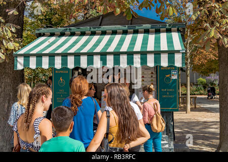 Eine Schlange von Menschen, die an einem Sommertag im Jardin du Luxembourg, Paris, Frankreich, an einem Erfrischungskioské Schlange stehen Stockfoto