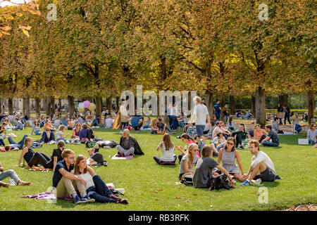 Leute sitzen auf dem Rasen im Jardin du Luxembourg Gärten genießen den Sommer Sonnenschein, Paris Stockfoto