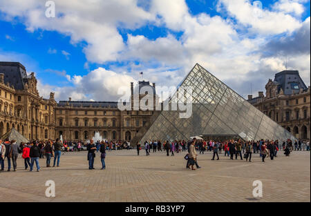 Paris, Frankreich - 25. Oktober 2013: Touristen, die vor der berühmten Pyramide und dem Louvre, einem der größten Kunstmuseen der Welt, spazieren Stockfoto