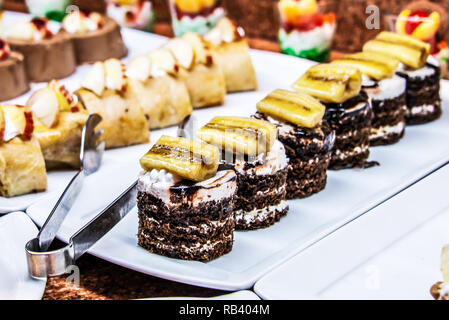 Close up viel leckeres Dessert Gebäck Kuchen Törtchen in einer Reihe. Frisch, bunt, bunt, Grün, Gelb, Weiß und Pink sweet berry Desserts, werden Stockfoto